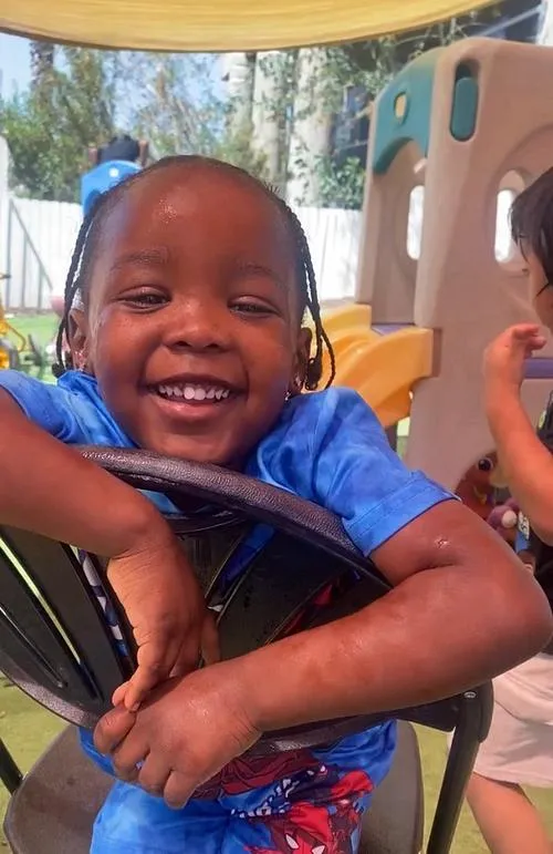 A KidsWay student beaming on the playground